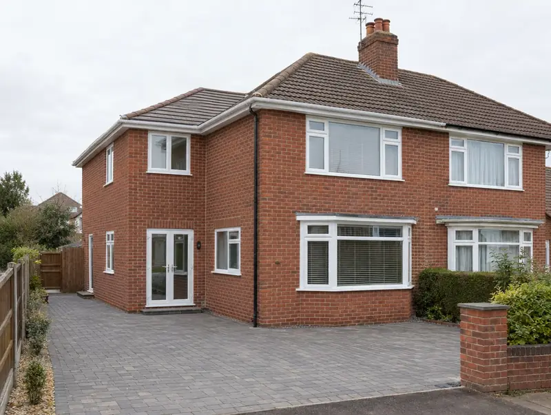 Two-storey side extension in matching red brick on a semi-detached house with a block-paved drive