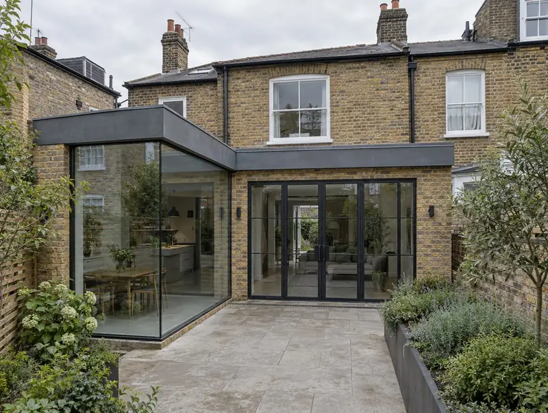 L-shaped wraparound extension with a frameless glass corner and steel-look doors on a London terrace